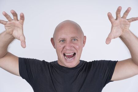 Portrait of an aggressive bald man, indoors, close up. Closeup shoot of caucasian bald man looking straight at camera. People and lifestyle conceptの写真素材