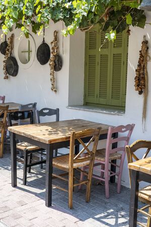 Front view of small cafe exterior. Table and empty chairs outdoor near the white wall. Tourist places. Typical Mediterranean restaurant, a place holidays in the summer. Kos island, Greeceの写真素材