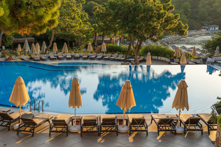 Empty sunbeds and closed parasols on morning, by the hotel pool. Swimming pool in luxury hotel resort near sea. Beautiful morning seascape. Bodrum, Turkeyのeditorial素材