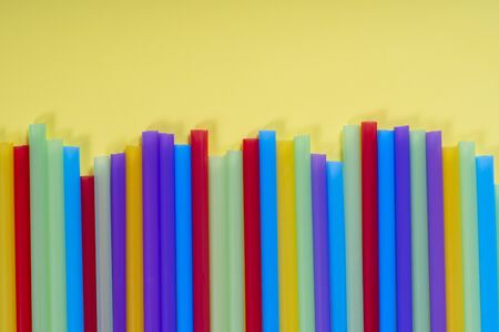 Background for a banner with plastic tubes isolated on yellow background. Frame for a banner with cocktail tubes. Party banner, cocktails bar. Elegant paper drinking straws. Close up, copy spaceの写真素材