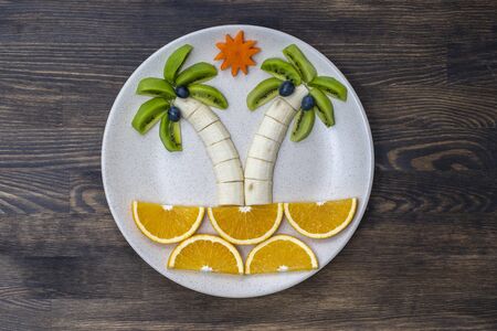 Creative fruit dessert with kiwi, banana, grape, carrot and orange. Concept children food. Fun and...