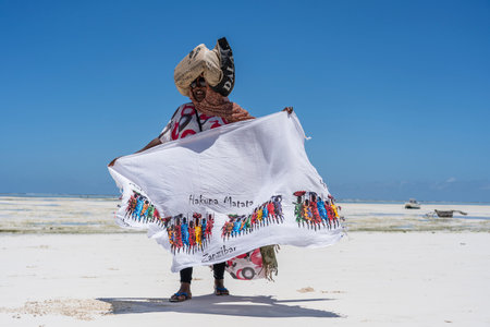Zanzibar, Tanzania - october 28, 2019 : African woman sell souvenirs and clothes for tourist near the ocean on the sand beach in Zanzibar island, Tanzania, east Africaのeditorial素材