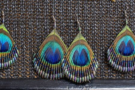 Peacock feather earrings for sale for tourists at the street market, close up. Island of Zanzibar,...