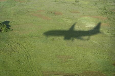 Shadow of the black plane shadow or silhouette in the green fields during the landingの写真素材