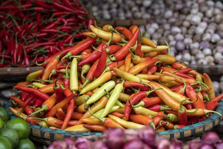 Orange, yellow and red sweet peppers for sale at street food market in the old town of Hanoi,...