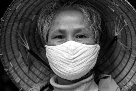 Sapa, Vietnam - march 06, 2020 : Ethnic Hmong old woman with protective mask on the face on a street of Sapa, North Vietnam. Black and whiteのeditorial素材