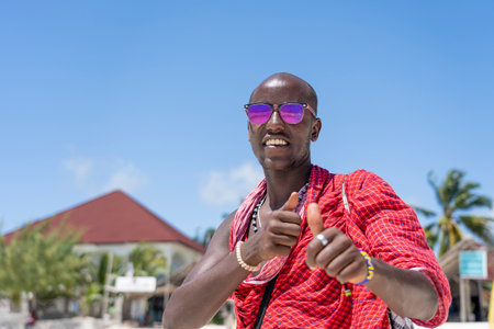 Zanzibar, Tanzania - november 11, 2019 : African man masai dressed in traditional clothes standing near the ocean on the sand beach, Zanzibar, Tanzaniaのeditorial素材