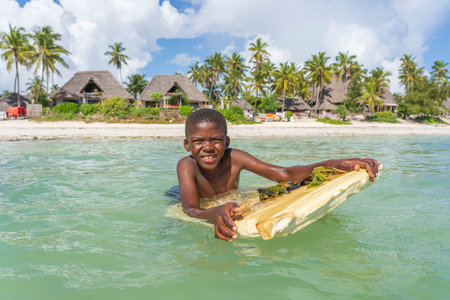 Zanzibar, Tanzania - december 01, 2019 : Happy african boy swims in sea water near tropical beach on the island of Zanzibar, Tanzania, east Africa, close upのeditorial素材