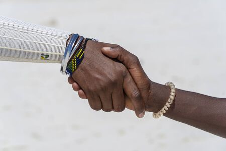 Tribal masai men making handshake in the tropical beach on island Zanzibar, Tanzania, East Africa,...