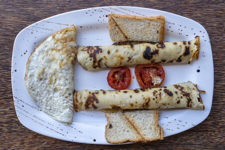 Tropical breakfast of scrambled eggs and wrapped banana pancakes in hotel restaurant, island...