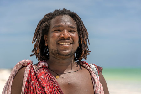 Zanzibar, Tanzania - january 04, 2020 : African man masai dressed in traditional clothes standing near the ocean on the beach of Zanzibar island, Tanzania, East Africa, close upのeditorial素材