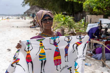 Zanzibar, Tanzania - january 15, 2020 : African woman sell souvenirs and clothes for tourist near the ocean on the sand beach in Zanzibar island, Tanzania, east Africaのeditorial素材