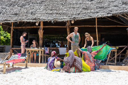 Zanzibar, Tanzania - november 11, 2019 : African women sell souvenirs and clothes for tourist near the ocean on the sand beach in Zanzibar island, Tanzania, east Africaのeditorial素材