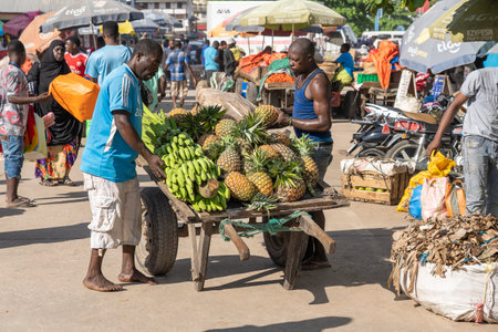 Zanzibar, Tanzania - november 14, 2019 : African man carrying a cart of tropical fruits at a local street food market on the island of Zanzibar, Tanzania, east Africaのeditorial素材