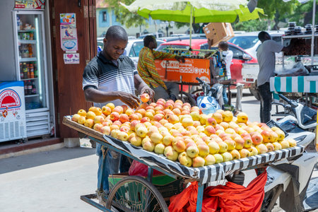 Zanzibar, Tanzania - november 25, 2019 : African man sells fresh apples at a local street food market on the island of Zanzibar, Tanzania, east Africaのeditorial素材