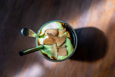Green avocado smoothie with black coffee and coconut chips in a Vietnamese restaurant during the morning breakfast, close up, top viewの写真素材