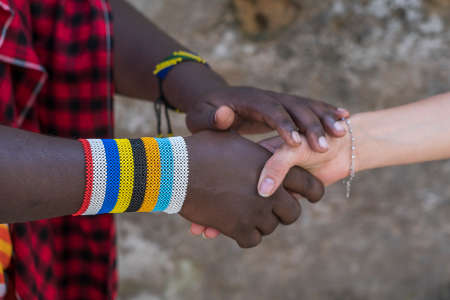 Masai tribal man with a caucasian girl making a handshake in the street on the island of Zanzibar, Tanzania, East Africa, close upの写真素材