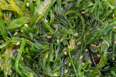 The seaweed salad with sesame seeds and red pepper in background. Top view, close upの写真素材