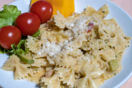 Pasta farfalle with cherry tomato and cheese in white plate, close upの写真素材