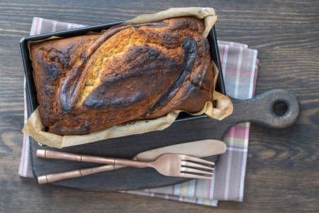 Homemade banana bread with cinnamon on a wooden background, close up, top view. Banana bread loaf, fresh baked from oven on wood table background, vintage rustic still life style. Concept of bakeryの写真素材