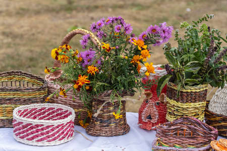 Beautiful flowers in a wicker vase on a table, outdoors, close up. Bouquet of violet, purple and...
