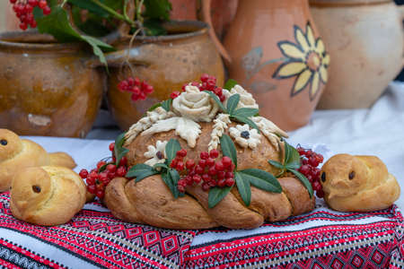 Ukrainian decorated fresh loaf with salt lies on the table, next to the embroidered towel. Ukrainian and Russian wedding traditions. Tasty pie, close upの写真素材