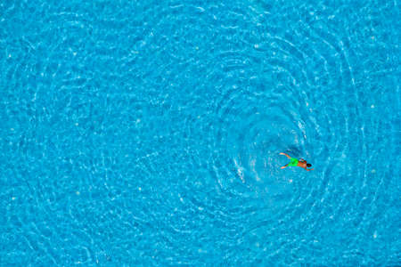 Boy swimming in a pool, top view. Summer travel and vacation concept