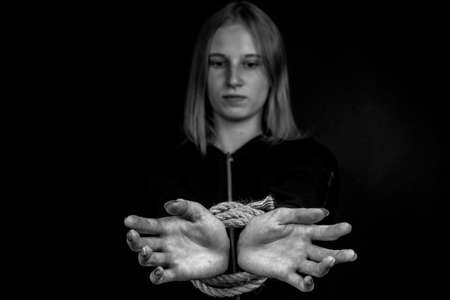 Portrait of young girl with bound hands on black background. Black and whiteの写真素材