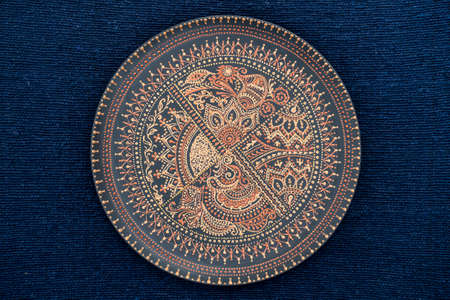 Decorative ceramic plate with black and golden colors, painted plate on the background of blue...