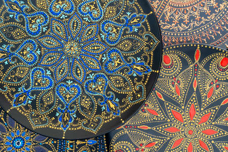 Decorative ceramic plate with black, blue, red and golden colors, painted plate on background, close...