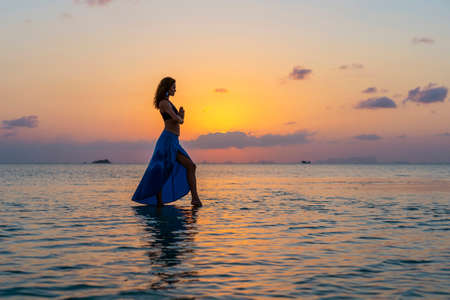 Young beauty girl dancing at tropical beach on sea water at paradise island at sunset, close up. Summer concept. Holiday travel.の写真素材