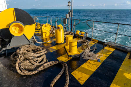 Yellow and black painted ferry deck boat along with the a thick mooring rope and blue sea water...