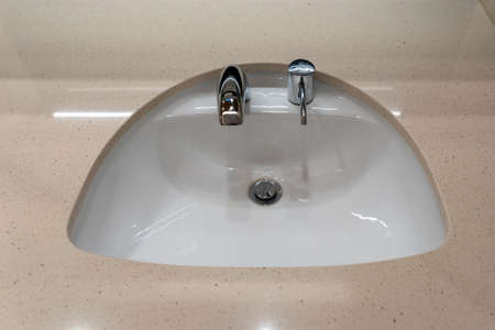 Faucets with washbasin in public restroom, close up. Modern sinks with mirror in public toiletの写真素材