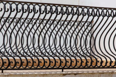 Black metal fence, close up. Beautiful decorative cast iron wrought fence with artistic forging....