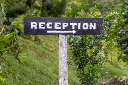 Text reception on a wooden board near tropical hotel in Borneo, Malaysia. Reception wooden sign inscription in the asian tropics, close upの写真素材