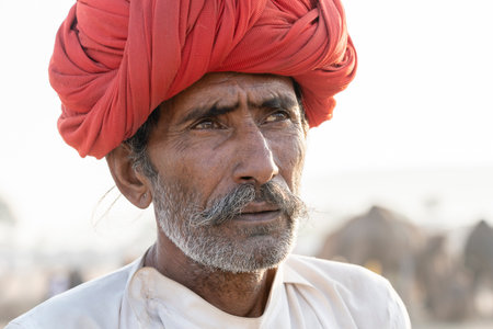 PUSHKAR, INDIA - NOVEMBER 14, 2018: Indian man in the desert Thar during Pushkar Camel Mela near holy city Pushkar, Rajasthan, India. This fair is the largest camel trading fair in the world.のeditorial素材