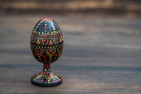 Colorful handmade wooden easter egg on a wooden background. Hand painted easter eggs with acrylic...