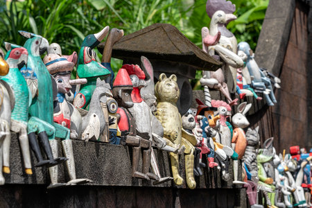 Old wooden souvenirs toys on the stone fence near the doll shop in Ubud, Bali island, Indonesia. Close upのeditorial素材