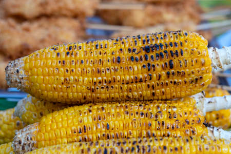 Grilled yellow corn for sale on street food market in Thailand, close up