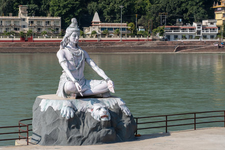RISHIKESH, INDIA - NOVEMBER 06, 2018: Statue of Shiva, Hindu idol near Ganges River water,...