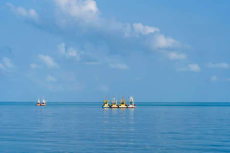 Fishing boats on the high seas against a blue sky next to Koh Phangan island, Thailand.