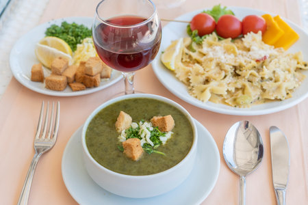 Green cream soup from spinach with croutons, cheese and fresh parsley in white bowl, close upの写真素材