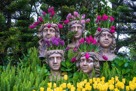 Flowerpots with red flowers in the shape of heads sculptures in a tropical garden in Danang, Vietnam, close upの写真素材