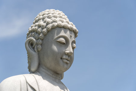 Detail of Buddha head marble statue in a Buddhist temple and blue sky background in Danang, Vietnam. Close up, copy spaceの写真素材