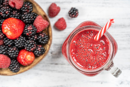 Fresh organic red smoothie in glass mug on white table, close up, top view. Refreshing summer fruit drink. The concept of healthy eating. Blackberry, raspberry and strawberry smoothieの写真素材