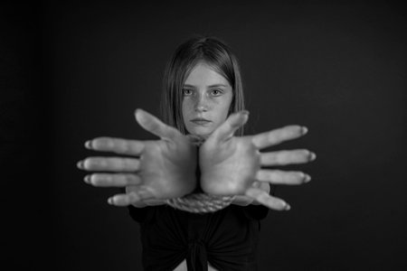 Portrait of young girl with bound hands on black background. Black and whiteの写真素材