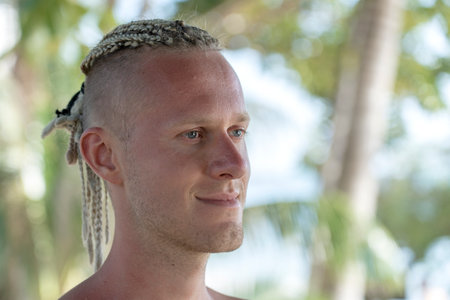 Portrait of a young guy with dreadlocks on his head in nature. Happy handsome man with dreadlocks on the tropical beach, close upの写真素材