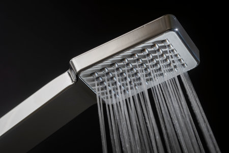 Water running from shower head in bathroom with black background. Concept home interior and design. Close upの写真素材