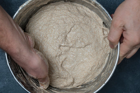 Male baker stretches out yeast-free dough for baking bread with his hands, close up, top viewの写真素材