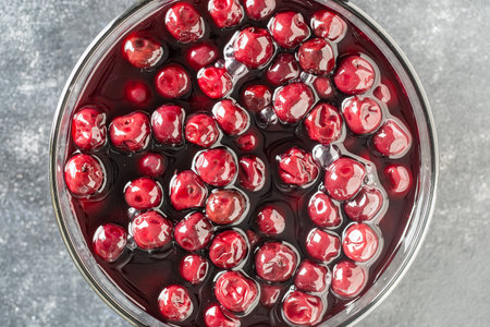 Cherries in alcohol in their own juice in a bowl, close up, top view. Fresh ripe red cherry soaked...